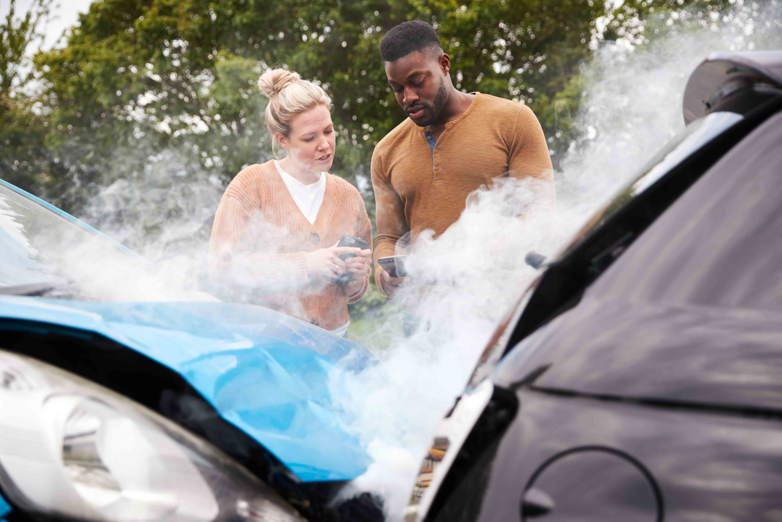 Two people examining damage after a car accident with concerned expressions, exchanging information.