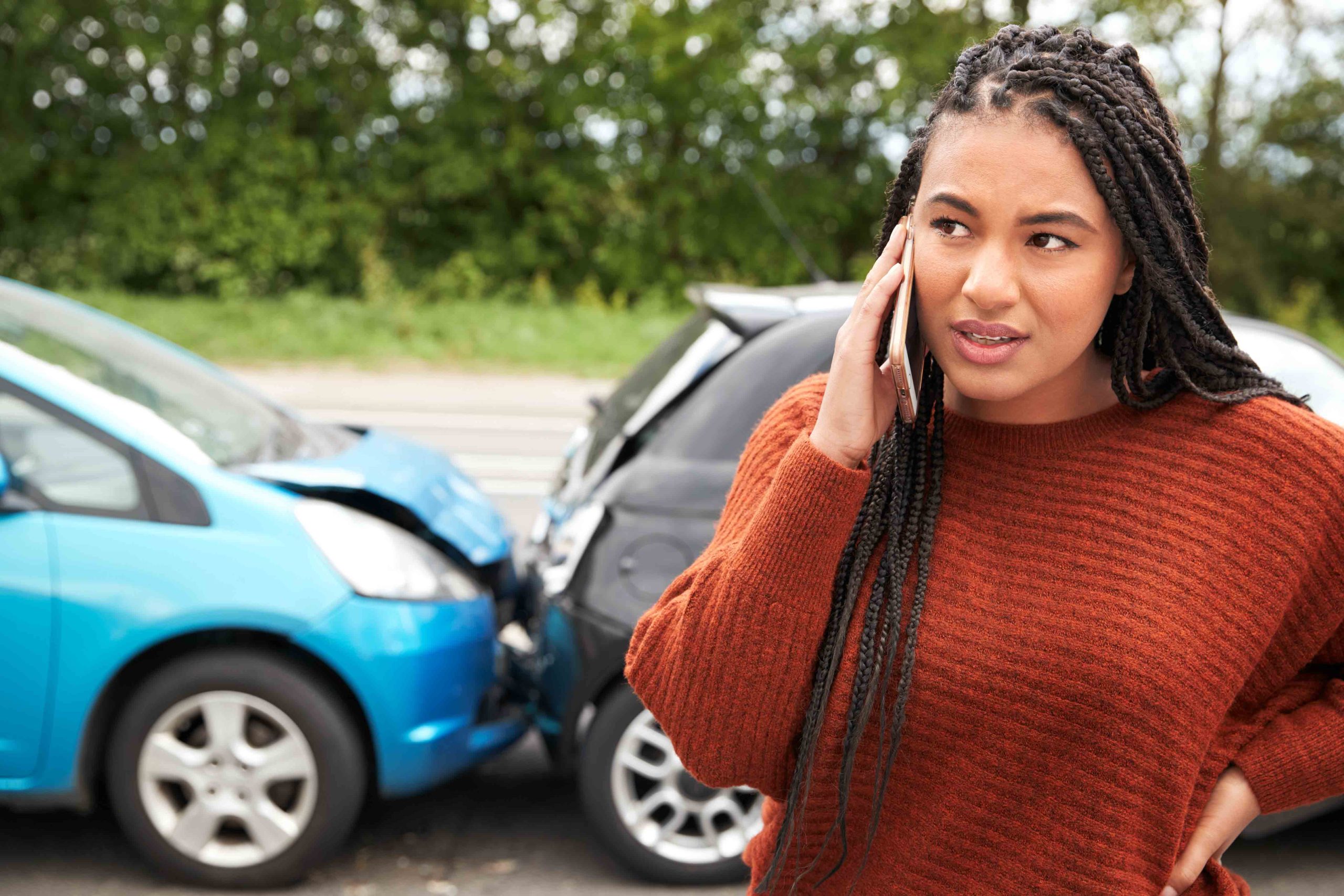 Concerned woman calling the insurance company after a rear-end car accident involving two vehicles.