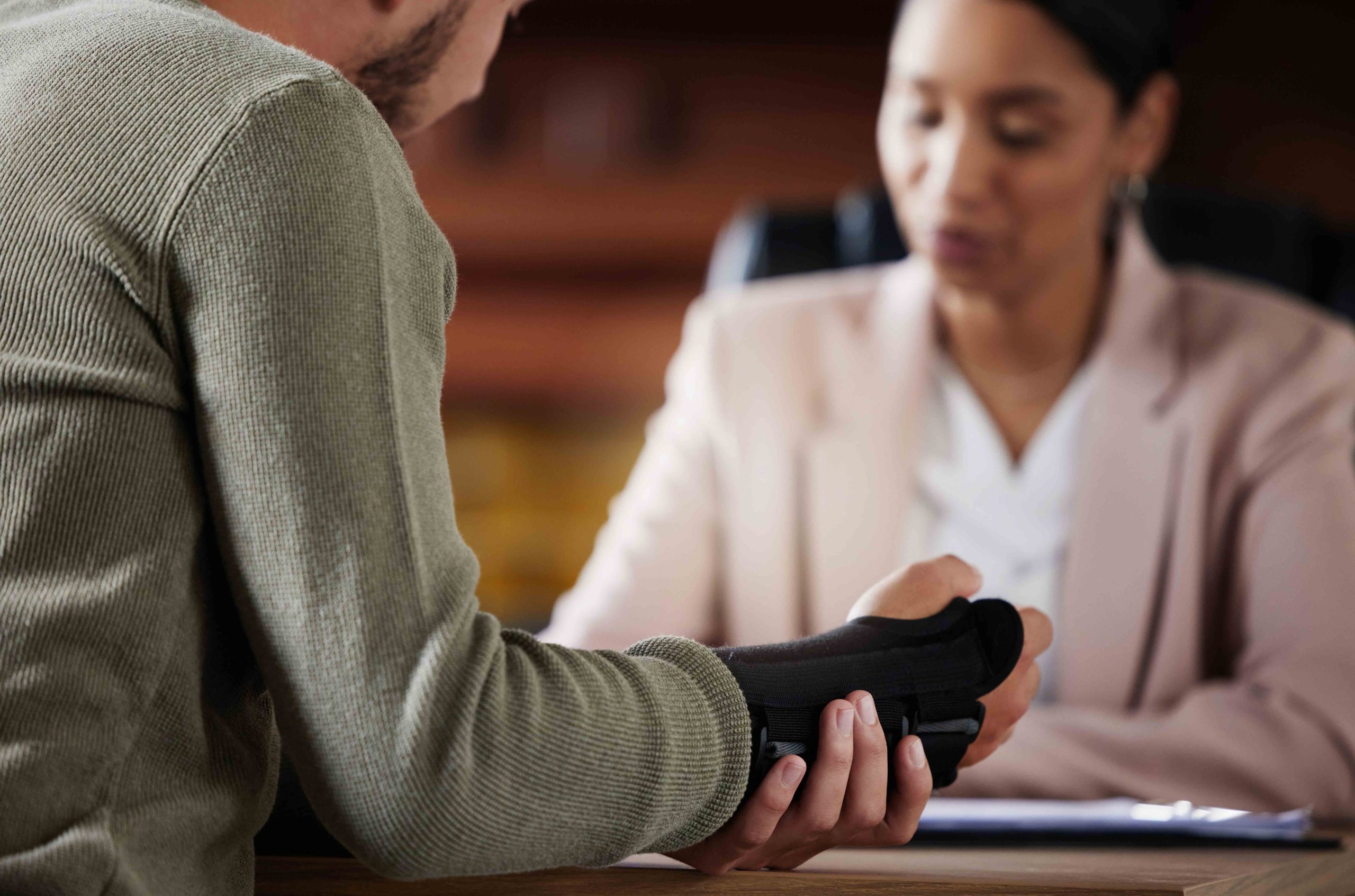 Personal injury lawyer consulting with a client wearing a wrist brace in an office.