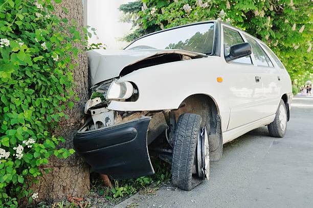 Front view of a car crashed into a tree, highlighting the dangers of defective car parts and the importance of pursuing legal action