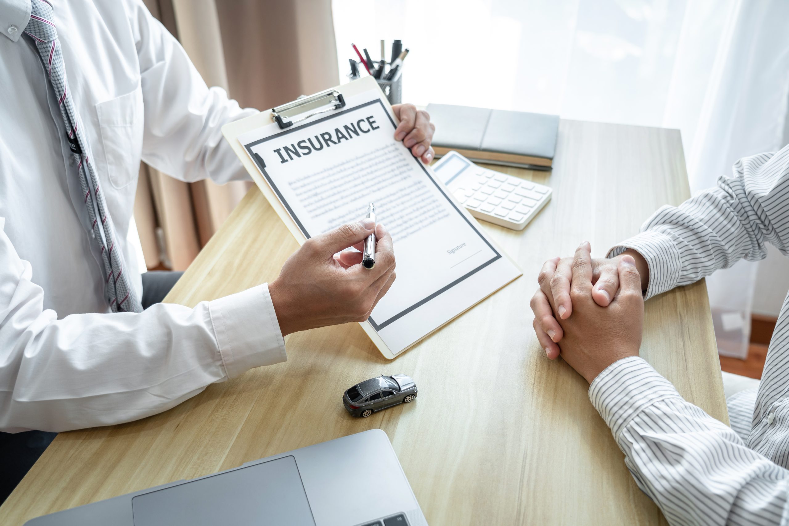 An insurance agent discussing a claim form with a client in an office setting.