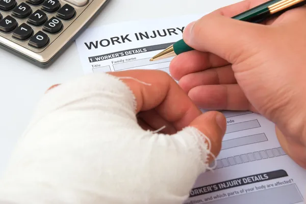 Injured worker filling out a workers' compensation claim form after a construction site accident