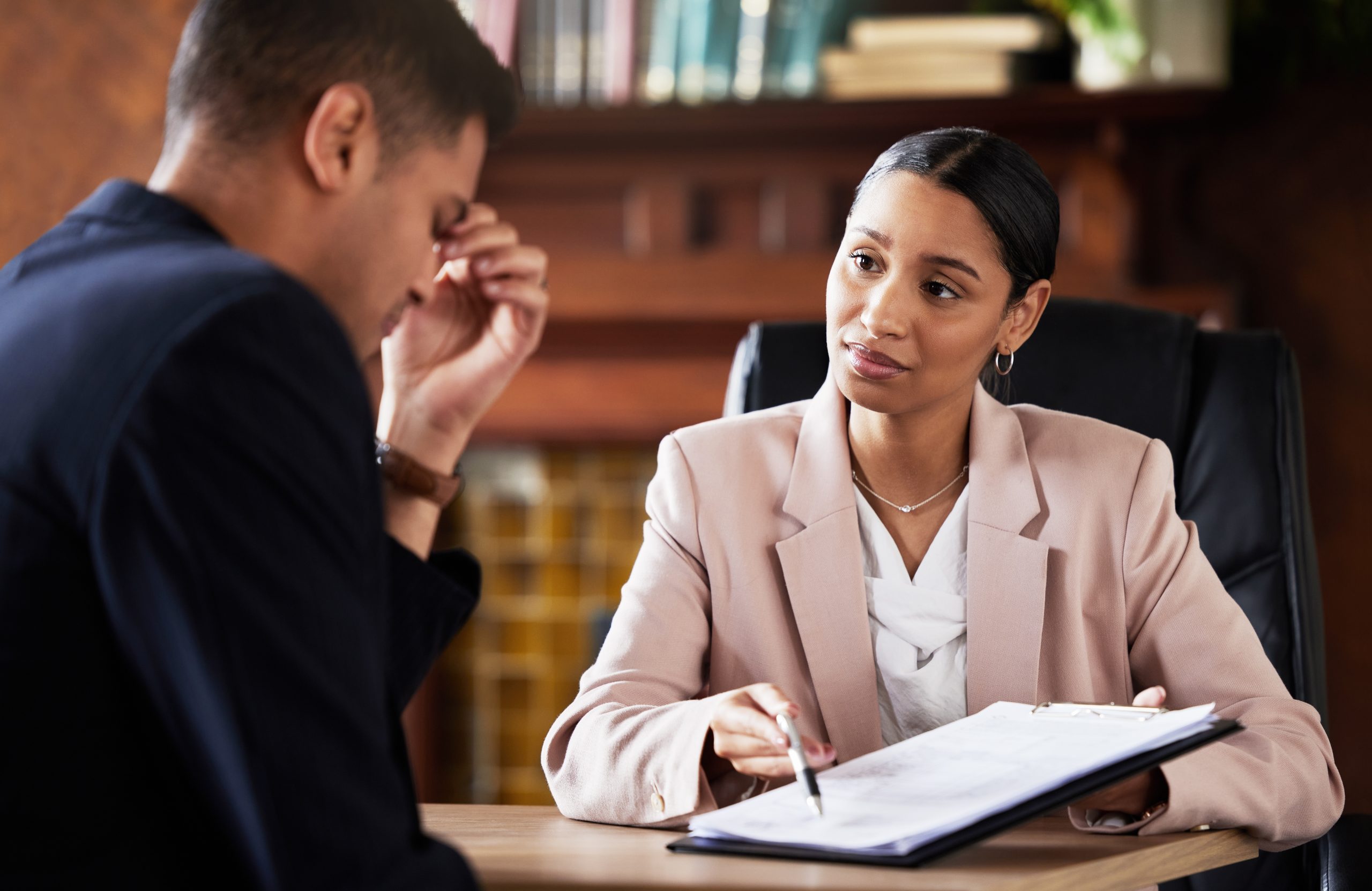 A serious discussion between a stressed man and a female injury lawyer, who is providing legal advice in an office setting