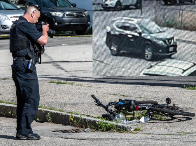 Police officer photographing evidence at the scene of a bicycle accident involving a CCTV footage of a hit-and-run vehicle.