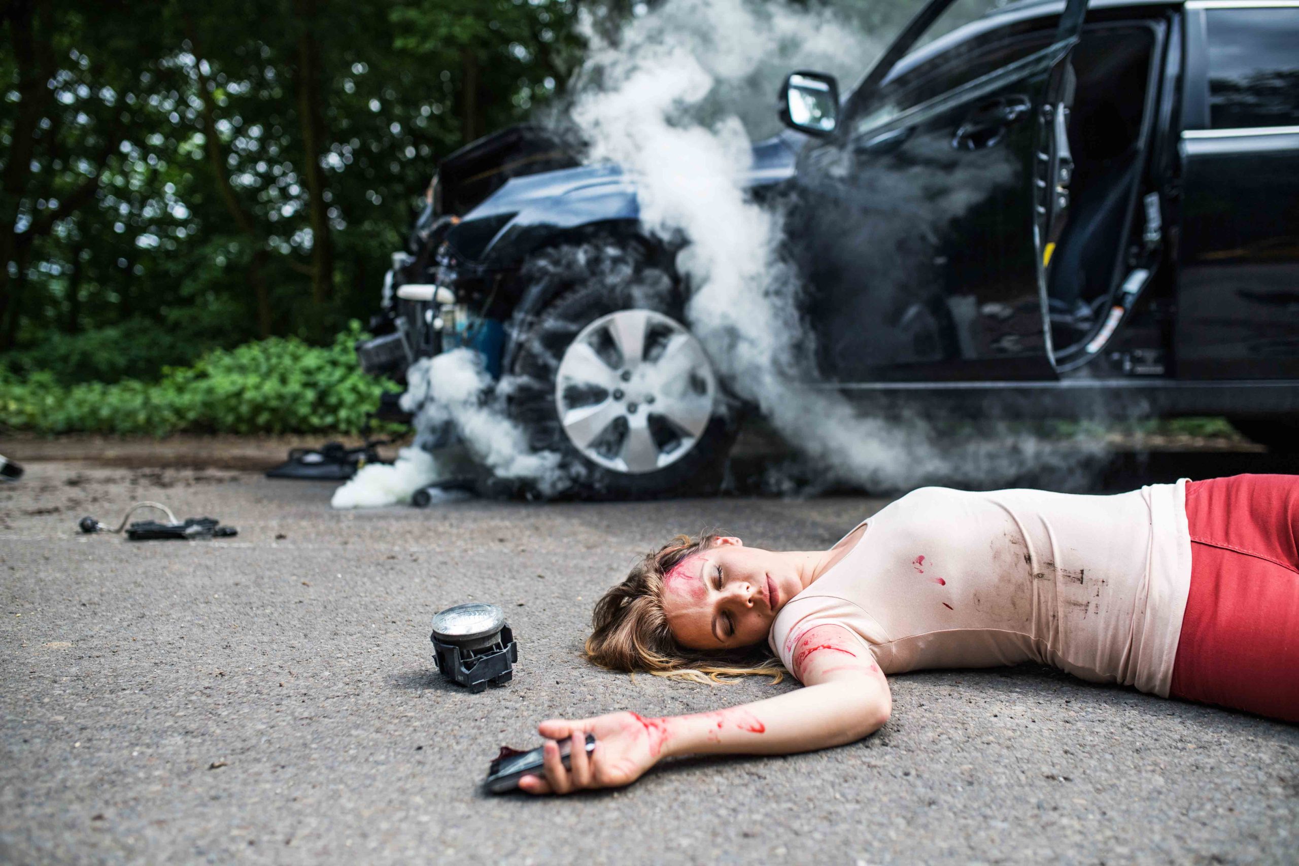 Woman taking photos of car accident damage on her phone, documenting the collision scene. 