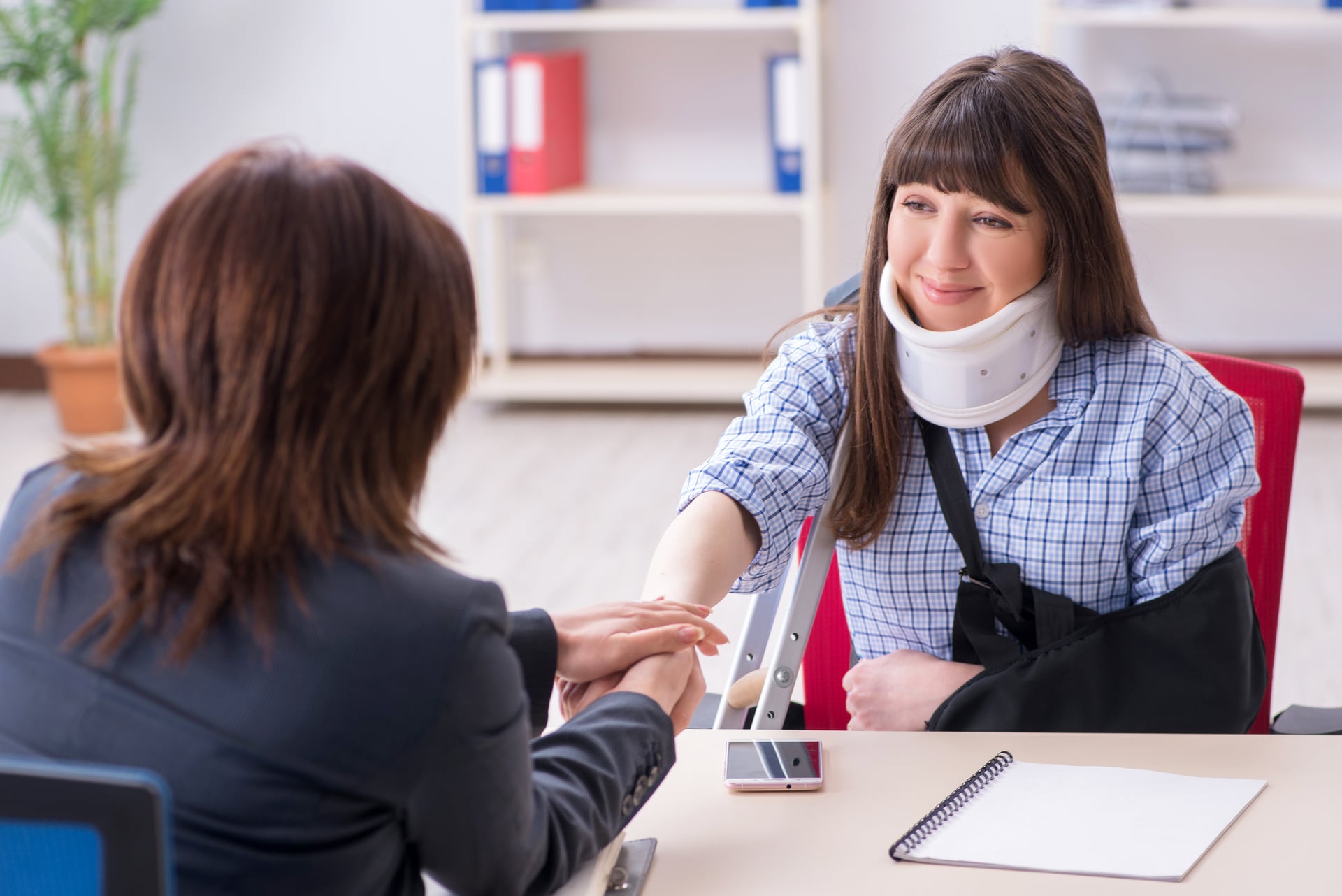 A woman in a neck brace and arm sling discussing her workplace injury claim with a legal representative in Texas