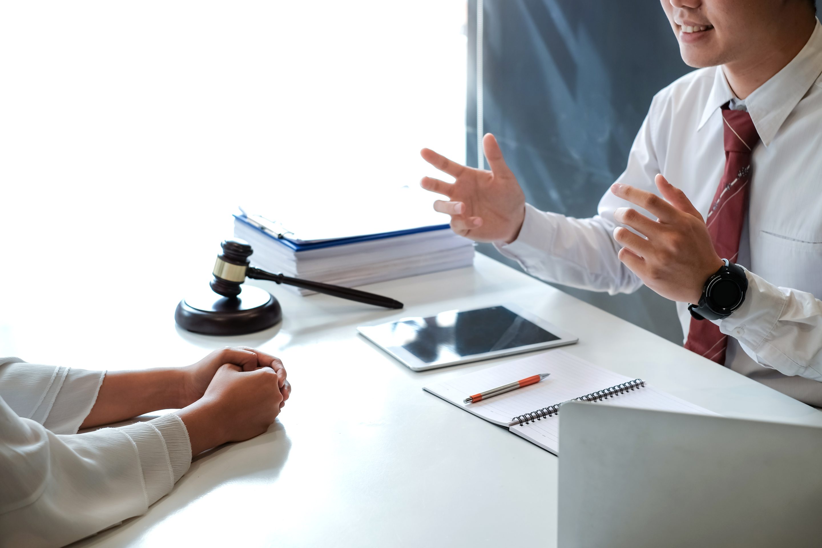 Smiling Attorney Roxell Richards, seated at a desk while shaking hands with client, ready to assist clients in need of justice