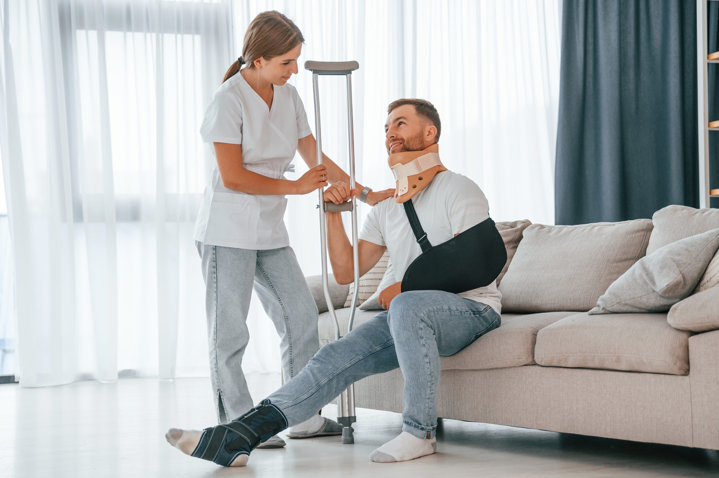 A man with a leg cast sits on a couch, supported by a woman, both reflecting on his hit-and-run injury