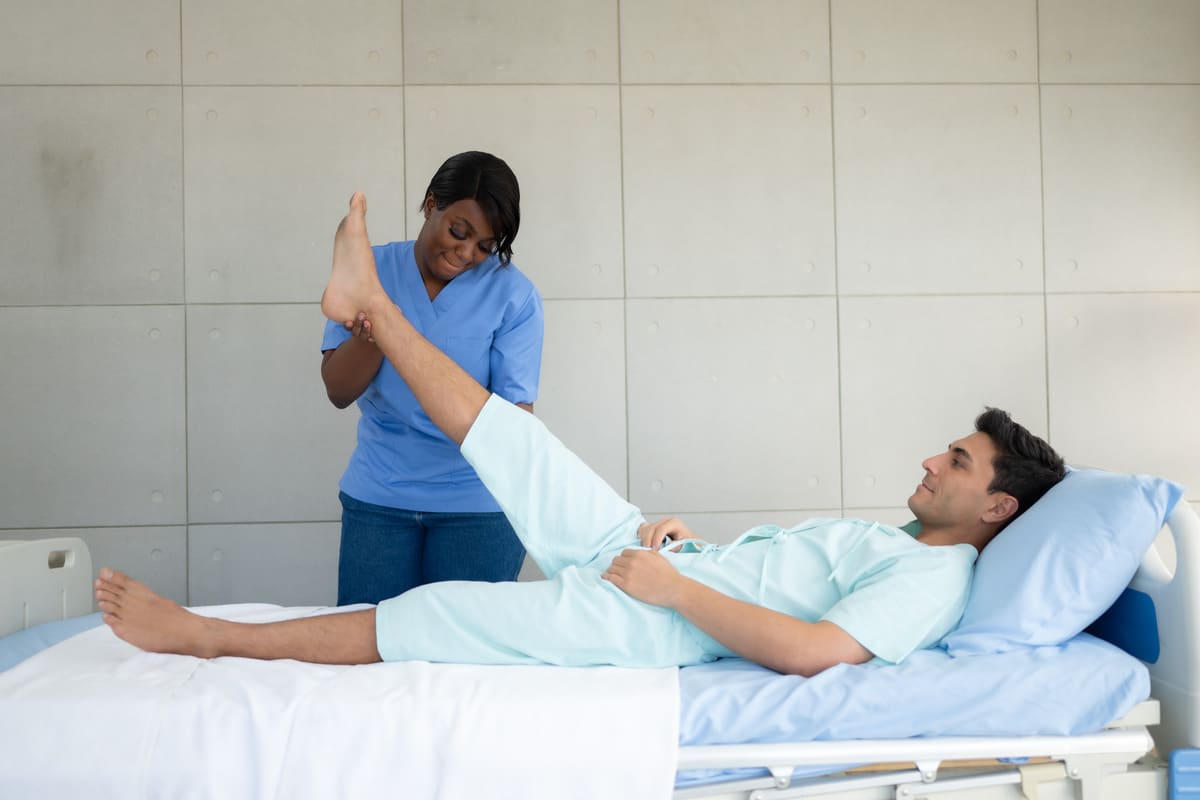 A nurse assists a patient in a hospital bed, who is recovering from injuries sustained in a pedestrian accident