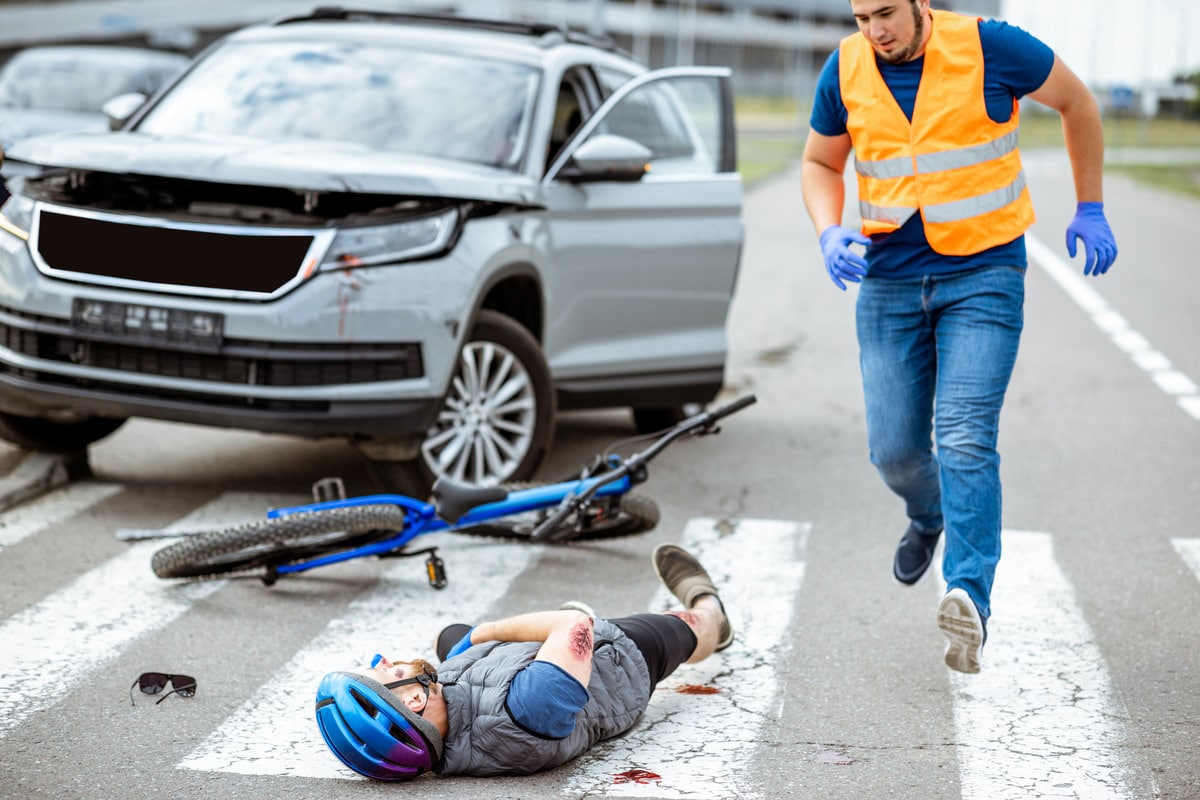 A man lies on the ground, injured after being struck by a car in a pedestrian accident