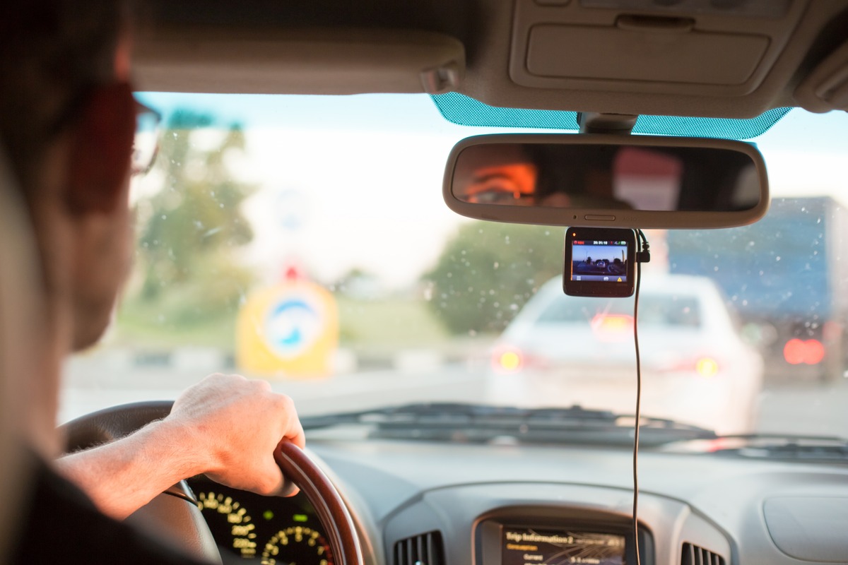 A man driving with a dashcam attached to the windshield