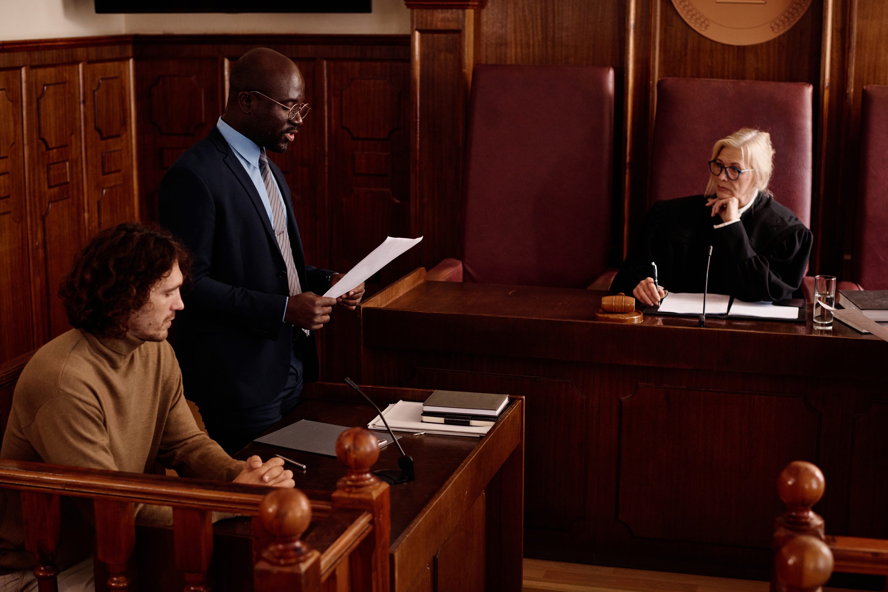 Smiling Attorney Roxell Richards, seated at a desk while shaking hands with client, ready to assist clients in need of justice