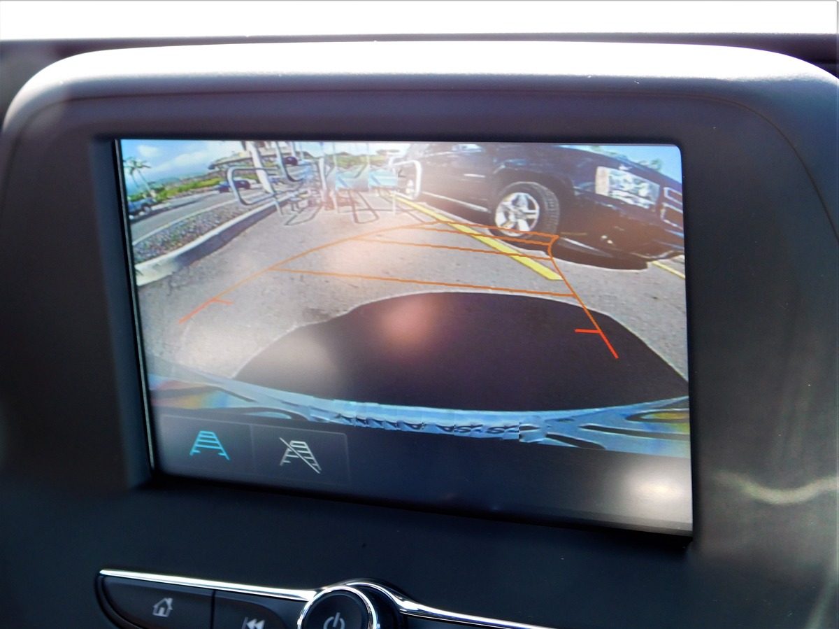 A rear view camera display in a car, showing another vehicle in a parking lot, indicating a potential accident