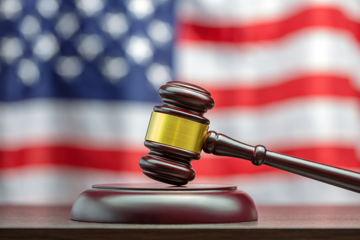 A judge's gavel rests on a wooden table, with an American flag in the background, symbolizing justice and Texas driving laws