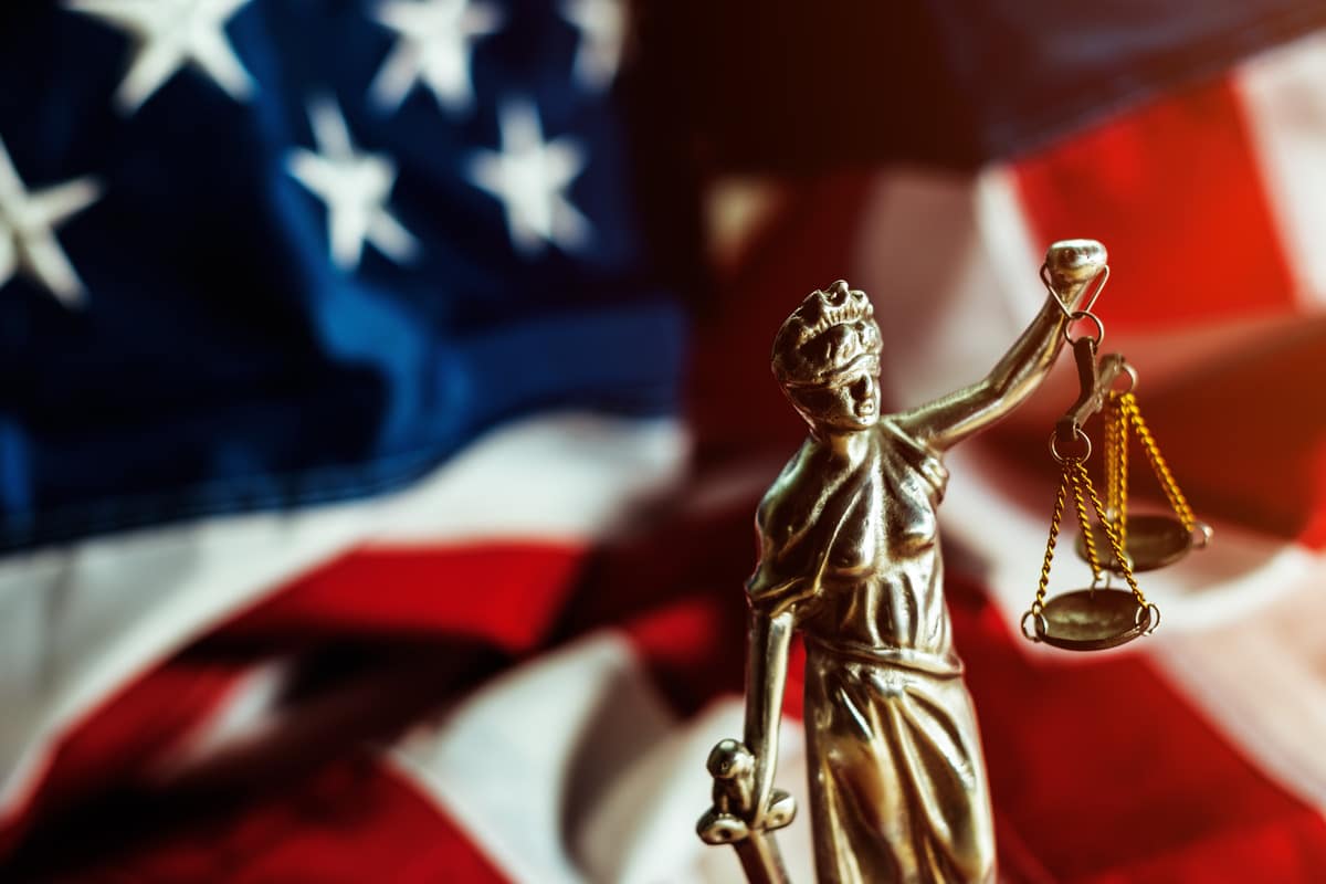 a gavel with the statue of lady holding the scales of justice on a table of a judge
