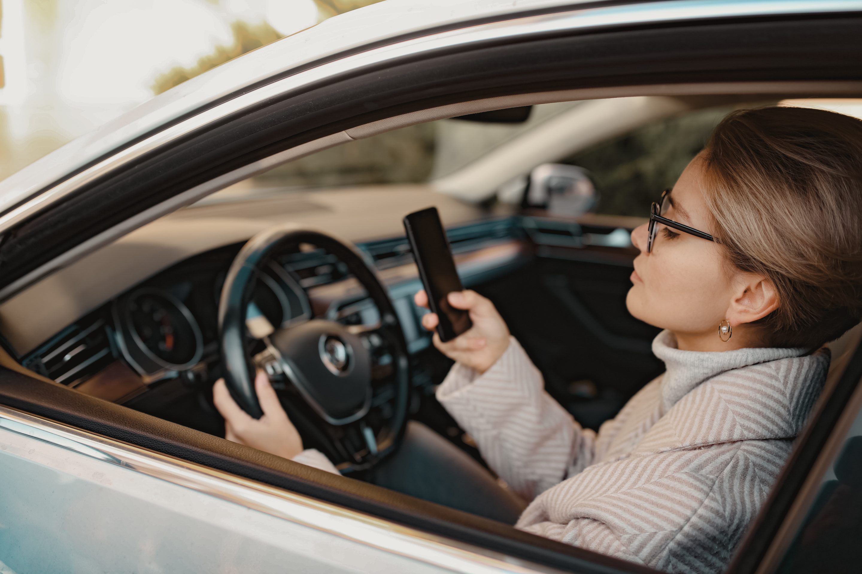 Woman driving while browsing on her phone