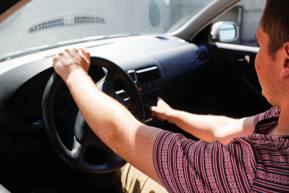 Man pushing a button on a car he's sitting in