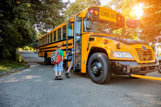 two children getting on the yellow school bus