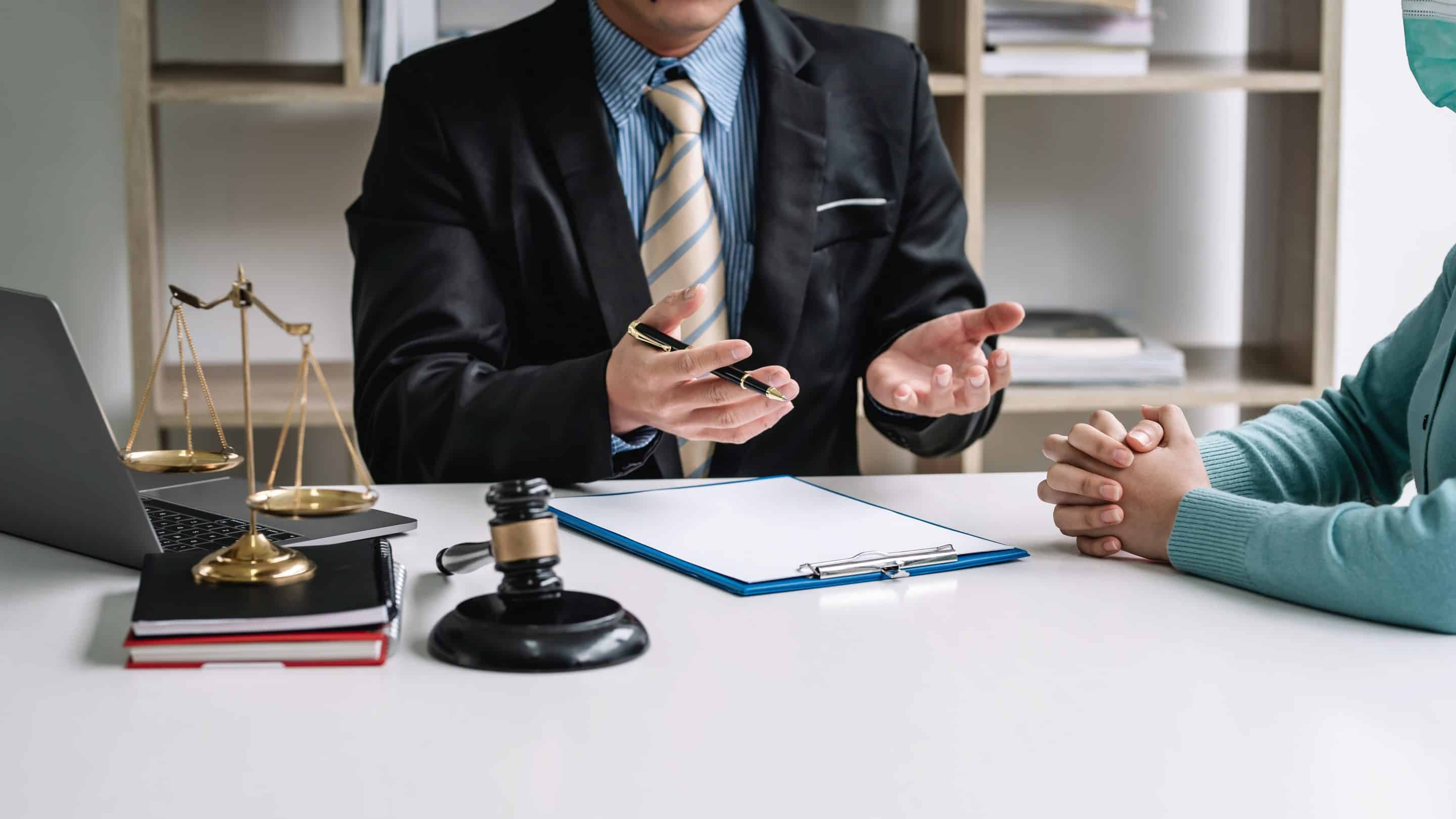 Attorney consulting with a client at a desk with a gavel and scales of justice for legal advice