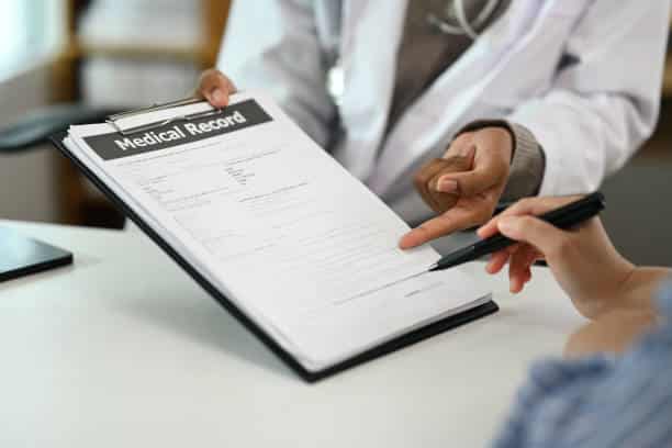 Doctor pointing to a patient's medical record for signature and consent during an office visit
