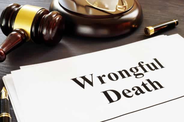 A document on a desk that reads "Wrongful Death" next to a judge's gavel and a lawyer's pen