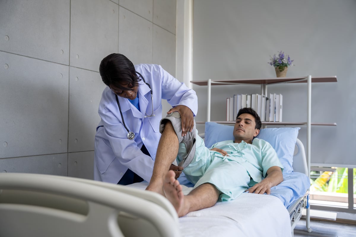 Orthopedic physical therapy session showing a healthcare professional treating a patient's knee injury in a medical clinic.