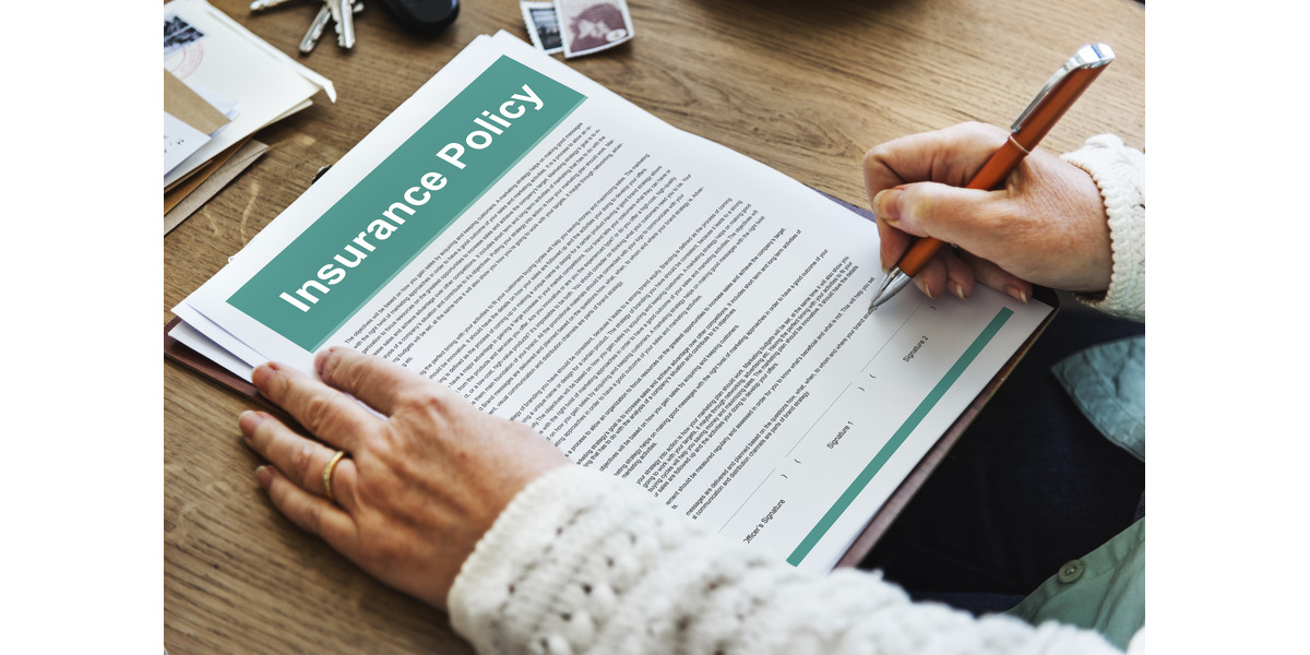 A policyholder reviewing and signing an insurance policy document, representing car insurance coverage, personal injury protection, and the process of filing an insurance claim