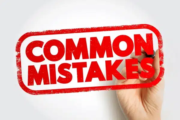 Hand holding red “common mistakes” stamp, symbolizing errors to avoid, business pitfalls, and learning from mistakes in marketing or strategy